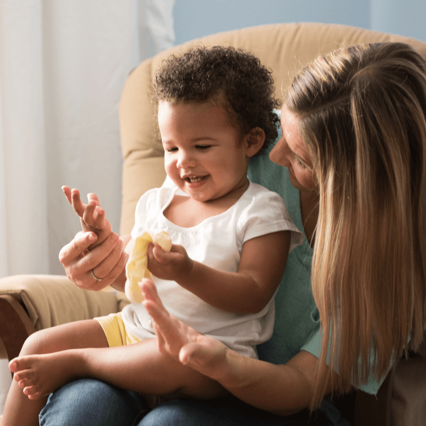 Madre sentada en una silla jugando con su hijo en el regazo.