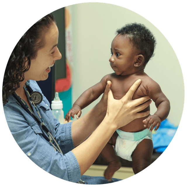 A doctor holds up a baby and smiles.