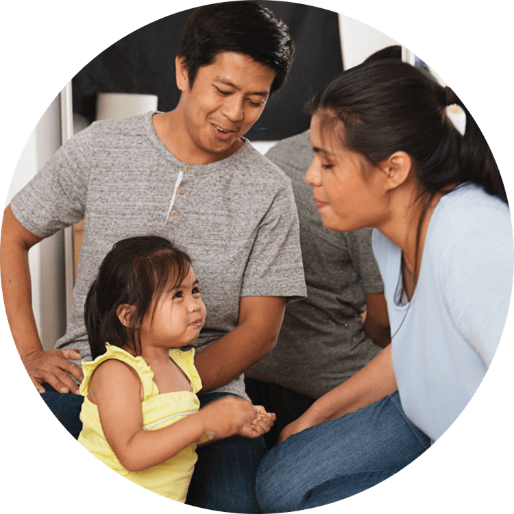 A father and mother blow raspberries to their daughter.