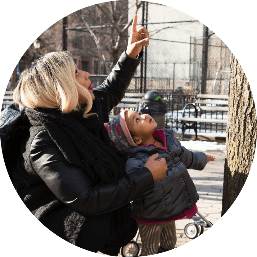 Una madre señala algo en un árbol y su hijo mira hacia arriba para ver qué es.